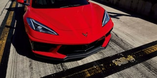 Three Quarters View of a Red 2025 Chevy Corvette Stingray with a Man and a Woman behind It
