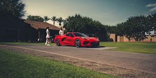 A Man with a Shopping Bag Walking Away from the Rear of a 2025 Red Chevy Corvette Stingray