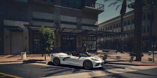 Three Quarters View of a Red 2025 Chevy Corvette Stingray with a Man and a Woman behind It